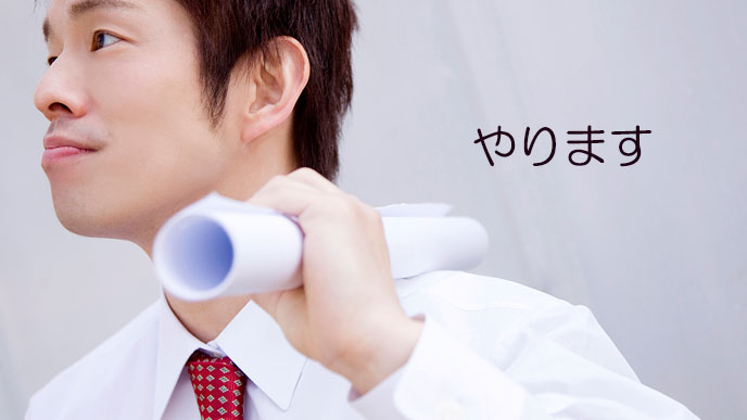 肩に設計図をのせる青年