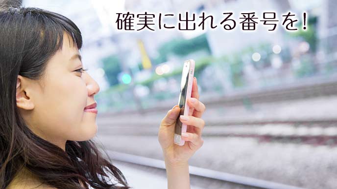 駅のプラットフォームで電話を受ける女性