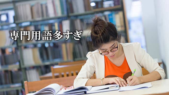 応募書類に専門書を参照しながら記述する女性