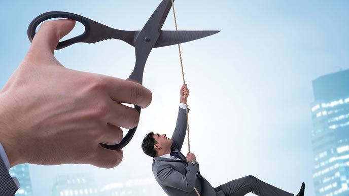 ぶら下がる綱を切られそうなビジネスマン
