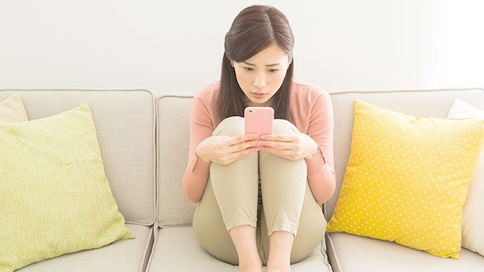 ソファでスマホを操作する女性