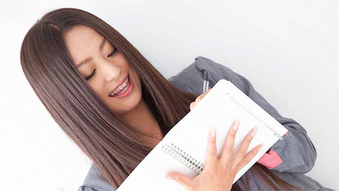 調べたことをノートにまとめてる女性