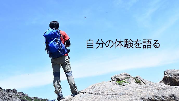 登山して山頂に立つ男性