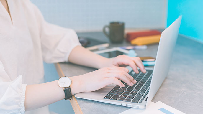 ノートパソコンで字を打つ人の手