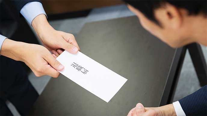 退職届を提出してるスーツを着た男性