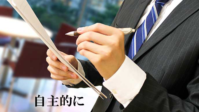 メモ書きしながら書類を見る男性