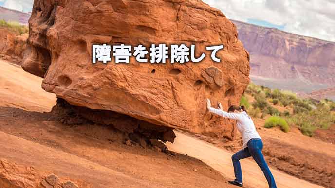 巨大な岩をどけようとする女性