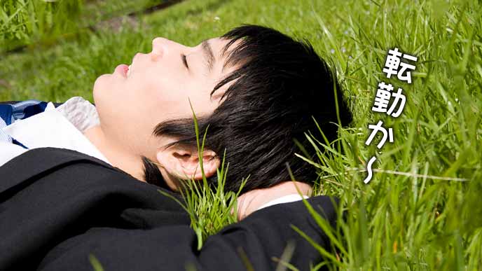 芝生の上に寝そべるスーツ姿の男性