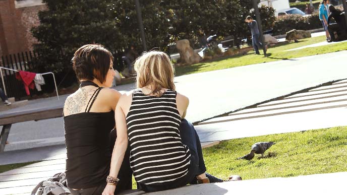 海外の大学ですわりこんで話しをする女性二人