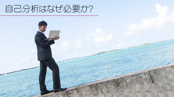 海の側をノートパソコンを持って歩くビジネスマン