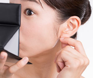 耳たぶを手鏡で確認する女性