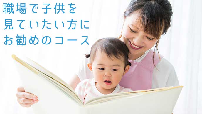 笑顔で子供に本を読ませる保育士の女性