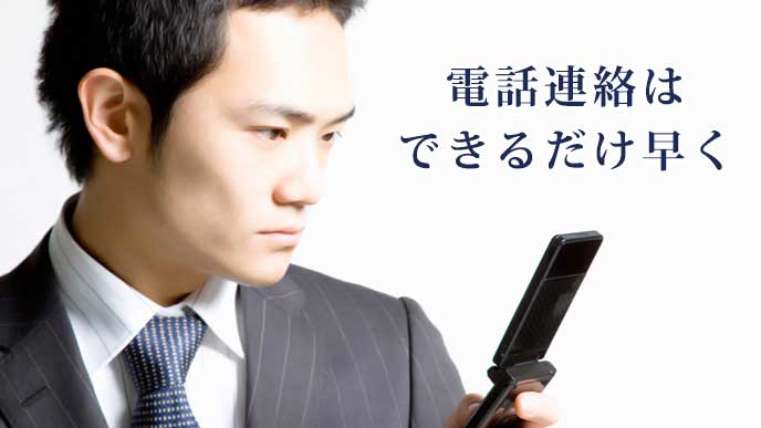 真面目な表情で携帯電話を使っているスーツ姿の男性