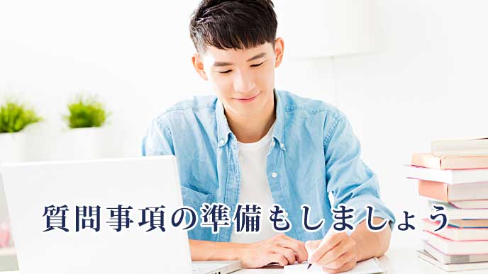 ノートパソコンを開きノートにメモを取っている男性