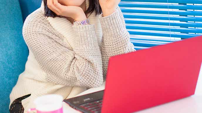 ラップトップの前で考える女性