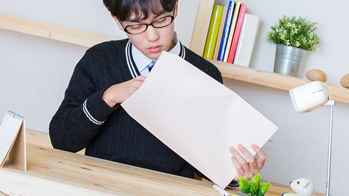 封筒に書類を入れる学生