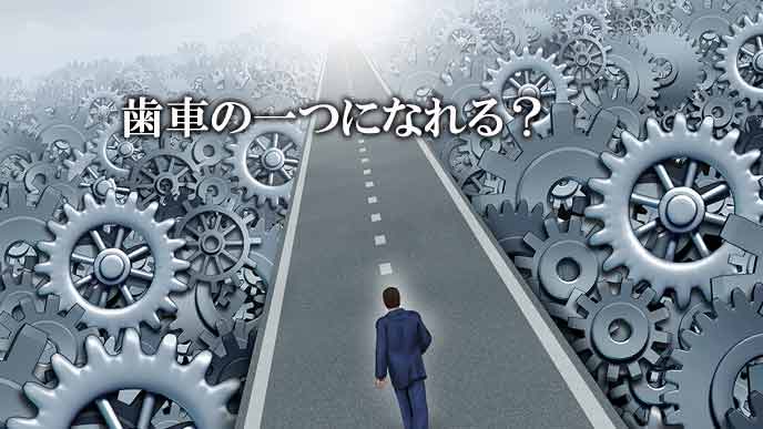 歯車の山の中に引かれた一筋の道を歩く人