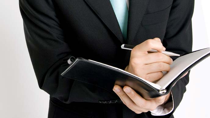 ノートにアイデアを書き込むスーツ姿の男性