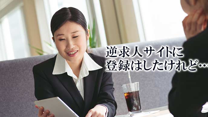 ノートパソコンを見ながら友達と話す就活学生