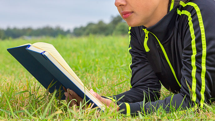 ラニング後にお外で本を読む女性