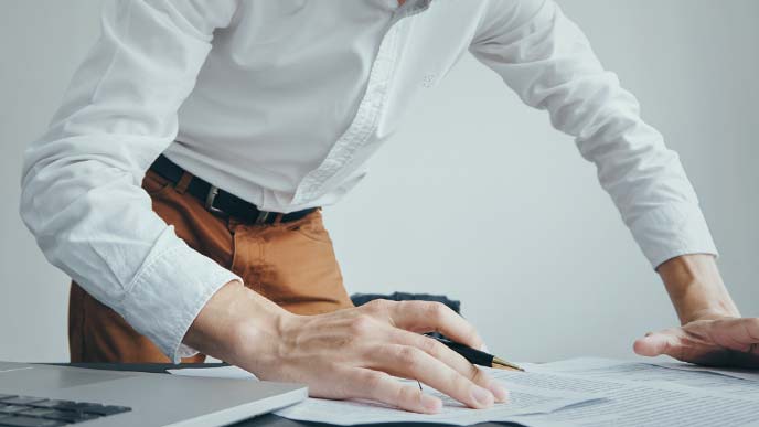 中腰で書き物中の男性クリエーター