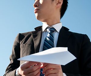 紙飛行機を飛ばそうとする男性社員