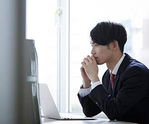 ノートパソコンの前に座って考える男性社員