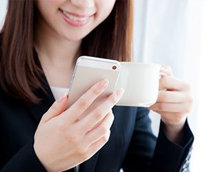 コーヒーを飲みならメールを読む女の人
