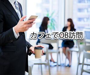 スマホとコーヒーのカップを持つ男の人