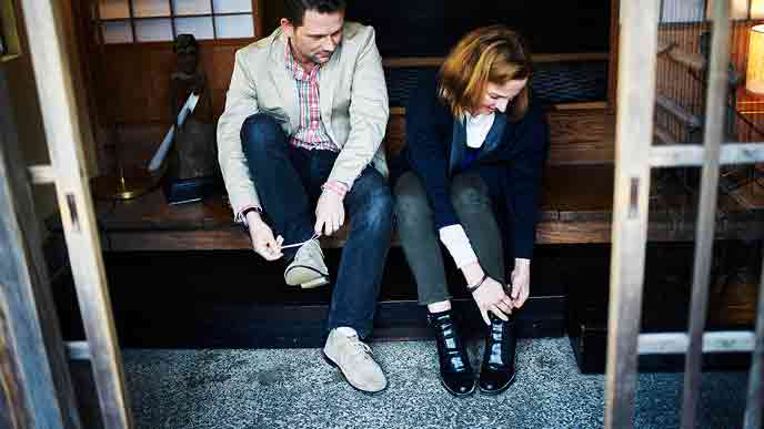 古い日本家屋の玄関から出かける外国人観光客