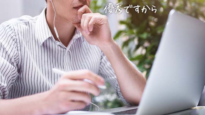 ノートPCを見ながら熱心にノートに書きこむ男子学生
