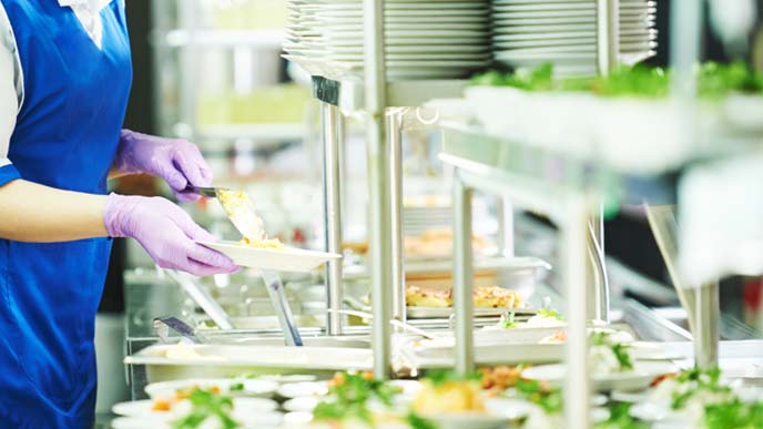 野菜をサーブする写真食堂のスタッフ